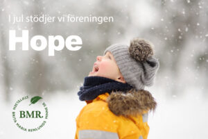 Barn klätt i vinterkläder och mössa med tofs tittar upp mot himlen. Det snöar.