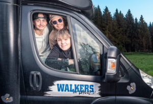 Tre män tittar ut genom ett bilfönster. Under fönstret står det Walkers på sidan.
